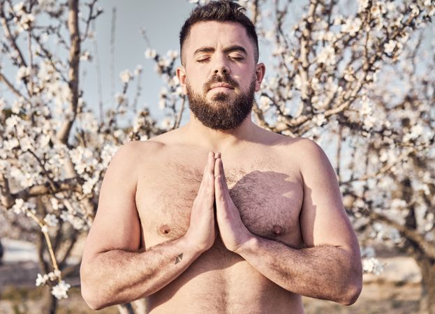 Shirtless man meditating in spring garden