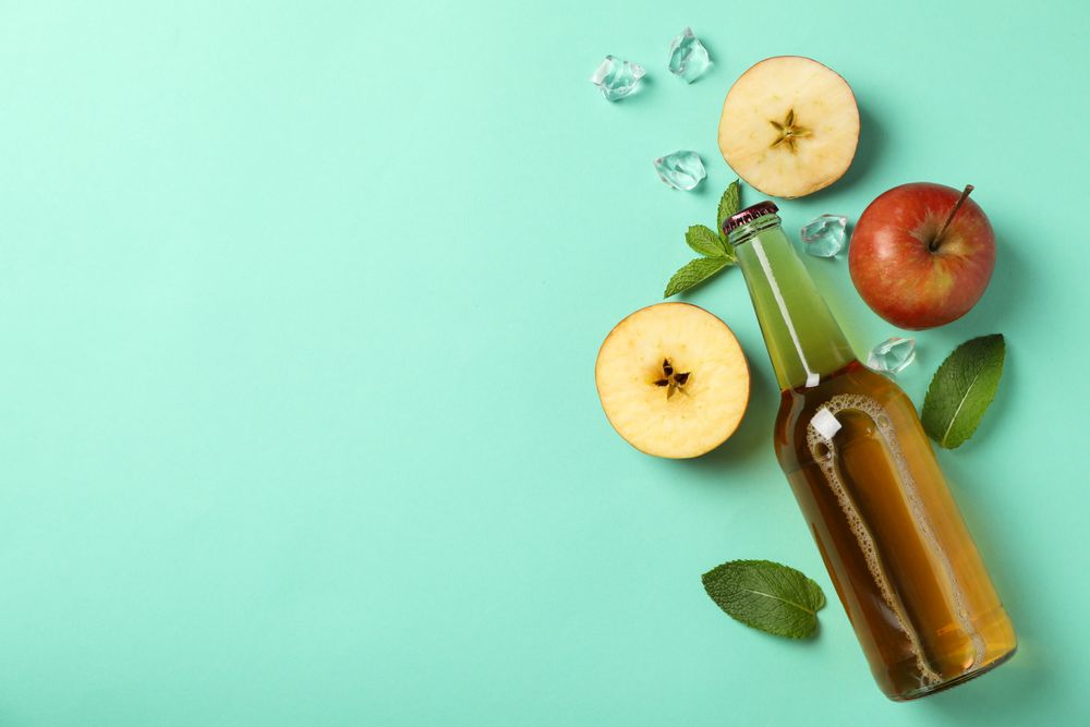 Composition with cider, apples and ice on mint background