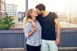 Couple kissing with man’s arm around woman’s shoulder