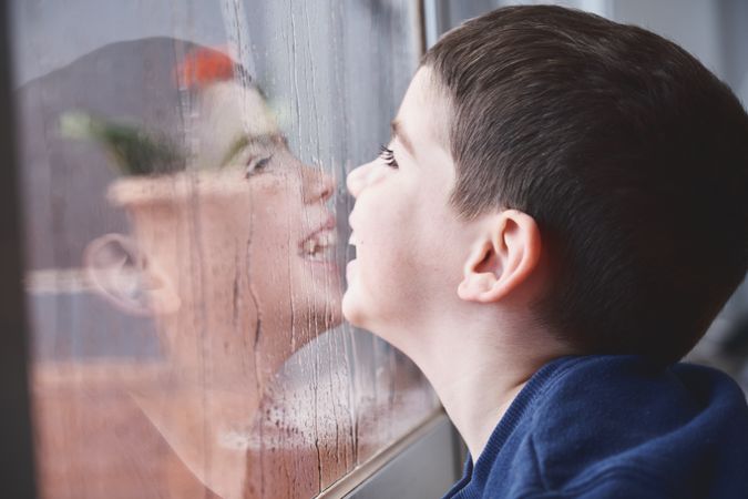 Boy breathing on wet glass