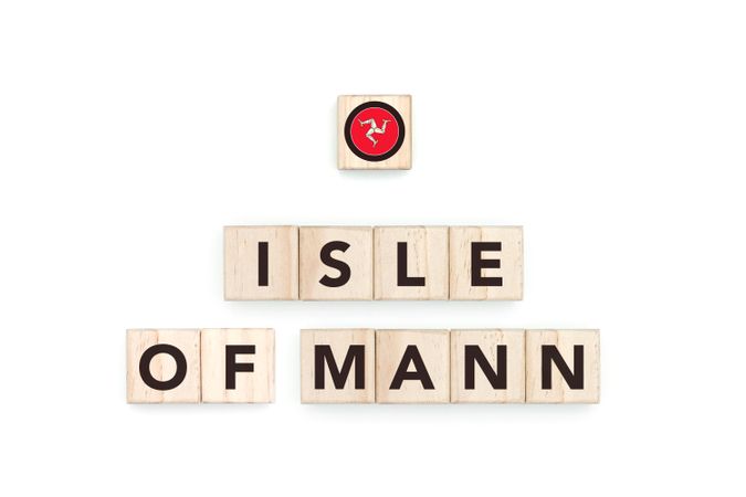 Wooden blocks bearing the name and flag of Isle Of Mann. Manx and British Culture, national identity, travel, and geography in a copy space design.