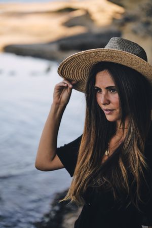 Cheerful woman holding hat in air