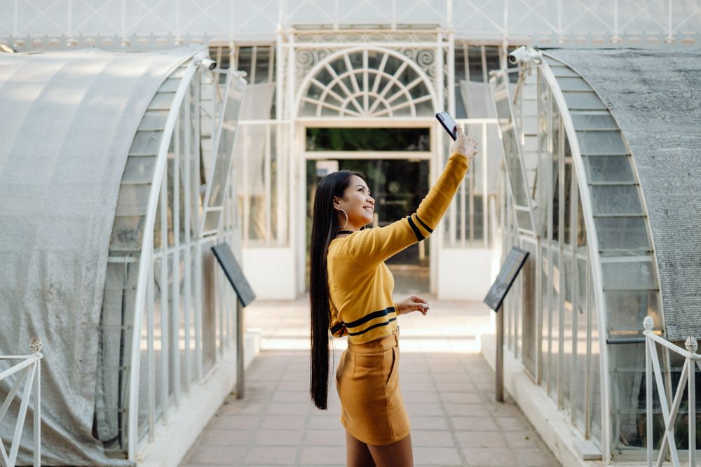 Smiling Asian woman taking selfie on mobile phone in geometrical space