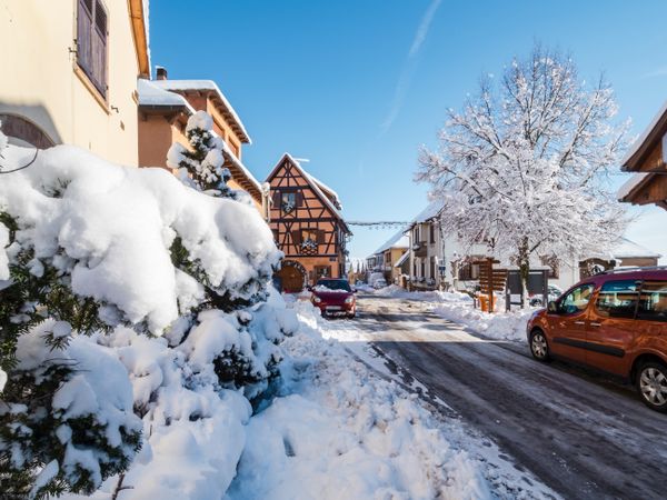 Sunny winter day. Snow-covered roofs of houses. Village in Alsace.