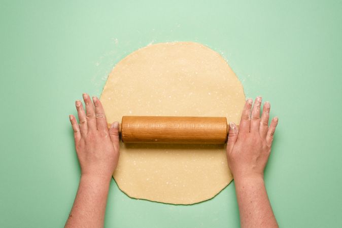Rolling out pie dough on mint background