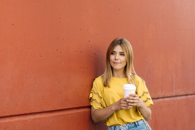Young blonde woman drinking takeaway coffee