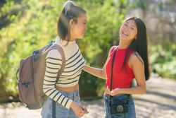 Two women chatting and standing on walking path in park