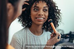 Makeup artist preparing a model for a photo shoot 4dmpLb