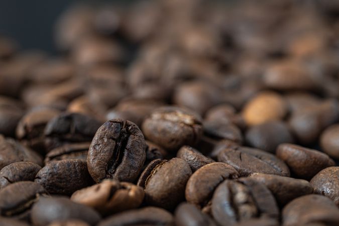 Macro low angle shot of roasted coffee beans piled together