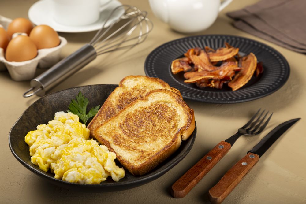 Breakfast. Scrambled egg with toast and bacon.