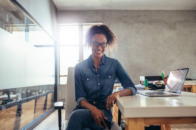 Positive young businesswoman sitting at office desk
