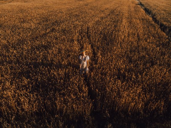 Woman in big round hat in middle of wheat field