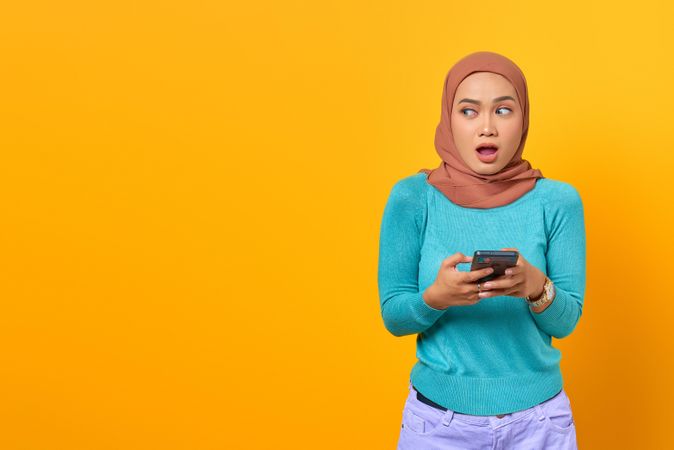 Surprised Muslim woman holding her phone