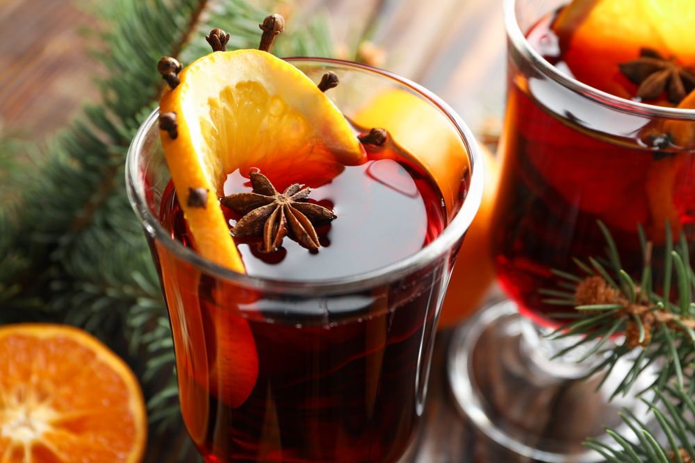 Glasses of tasty mulled wine with orange on wooden background, close up