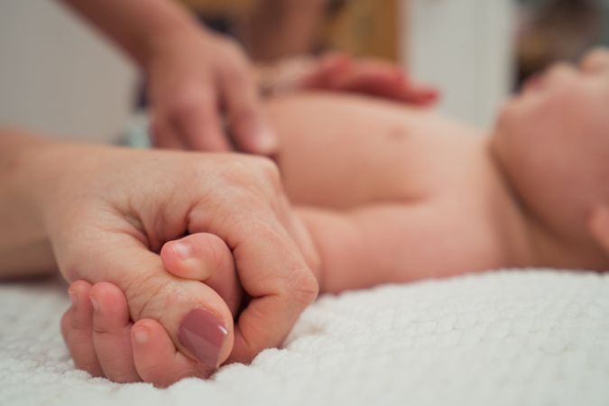 hand holding little baby on bed