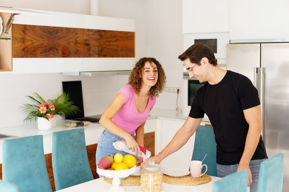 Happy adult couple standing near dining table and having fun