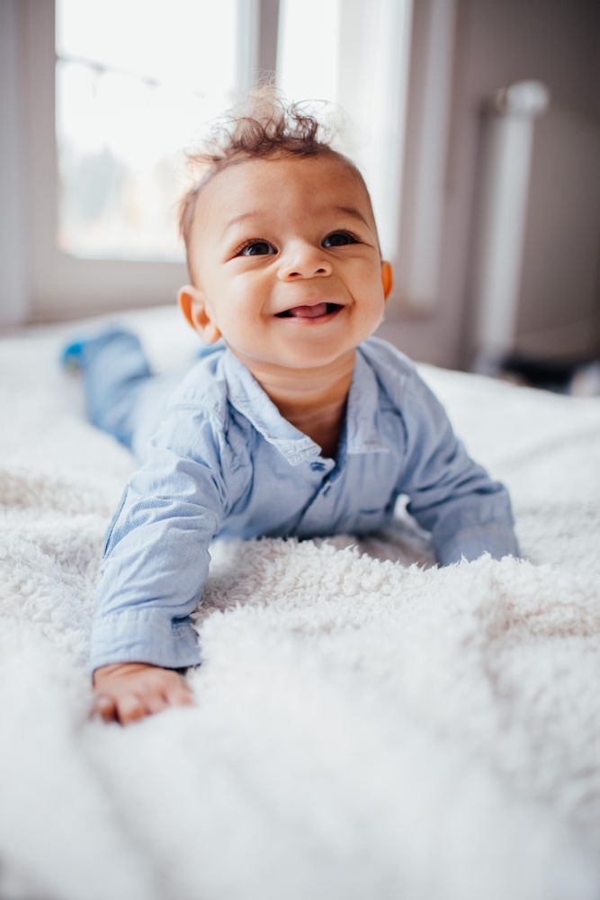 Smiling baby boy lying on his stomach with his head up