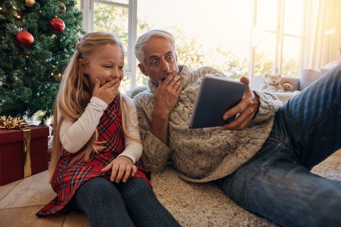 Surprised grandfather and granddaughter looking at digital tablet