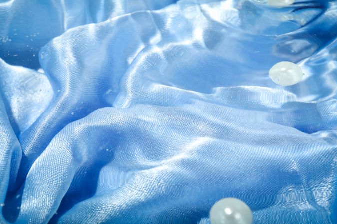 Top view of clear water with blue fabric and pearls