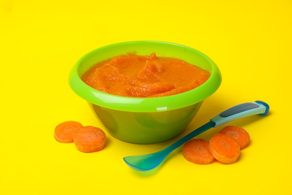 Bowl with vegetable puree on yellow background. Baby food