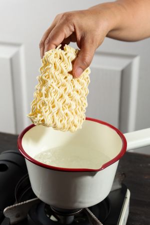 Selected Focus Put Dried Instant Noodle to the Pan with Boiled Water