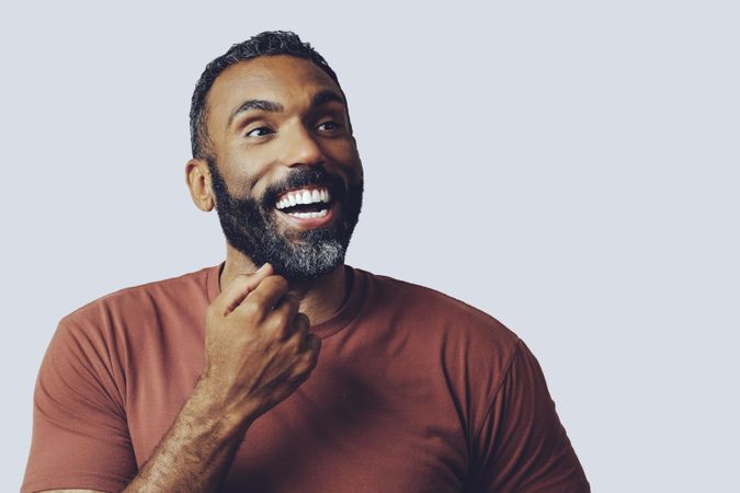 Head shot of happy Black male looking up in grey studio