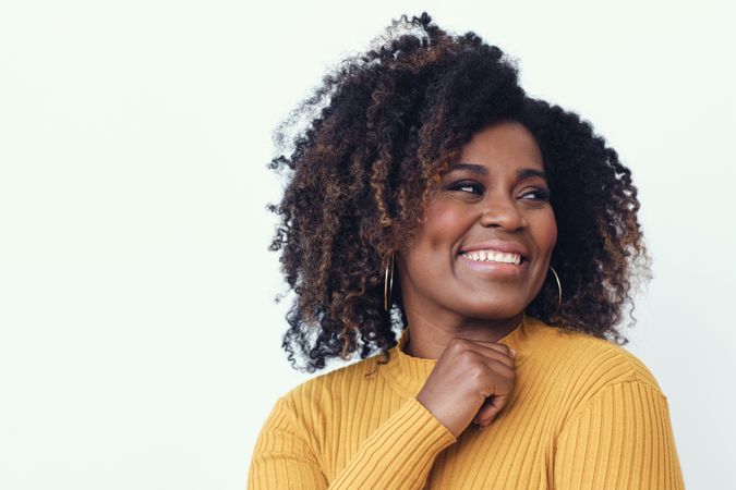 Studio shot of a smiling Black woman in yellow shirt