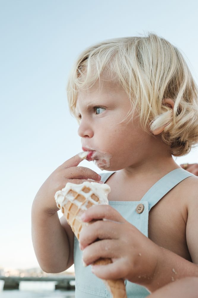 Boy licking ice cream from finger on beach