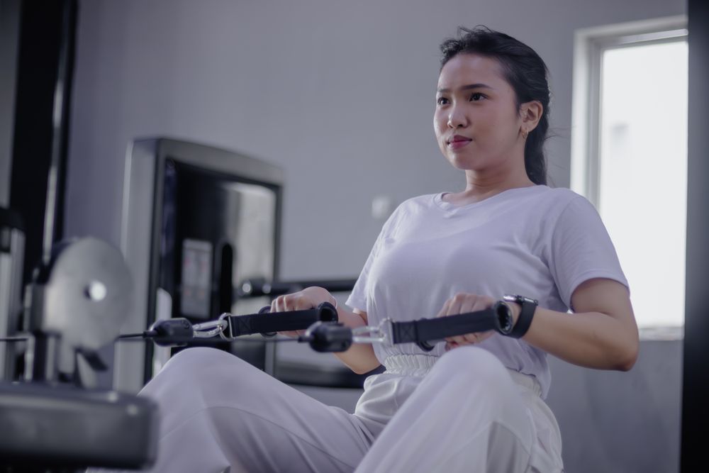 Focused woman using rowing machine for strength training session