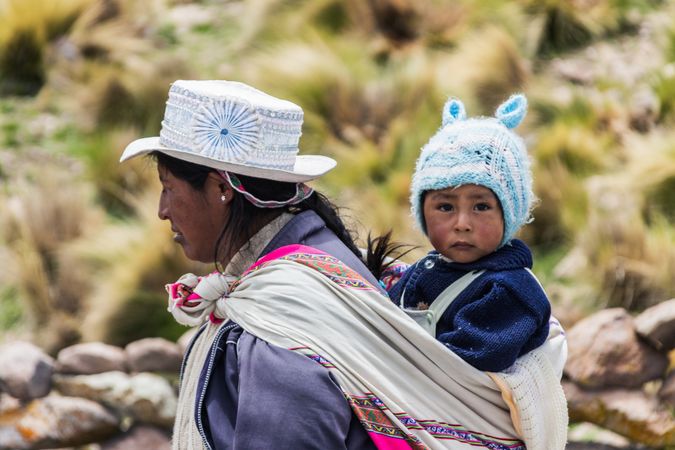 Peru - January, 02 2012: Peruvian woman carrying baby on back