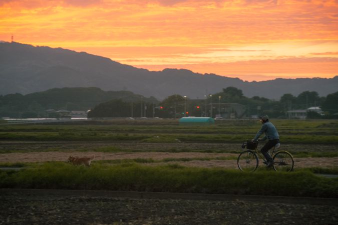 Man riding a bicycle near mountainous landform at sunset