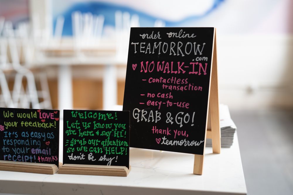 Signs on table at entry to coffee shop requiring no walk-in customers during social restrictions
