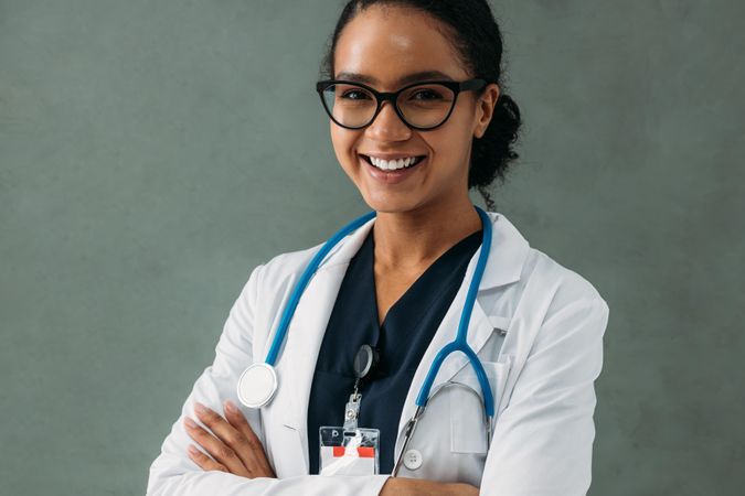 Portrait of smiling female Black doctor in lab coat and stethoscope with her arms crossed