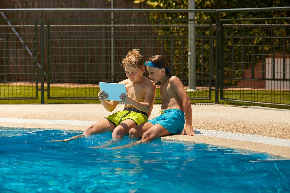 Boys on poolside browsing tablet