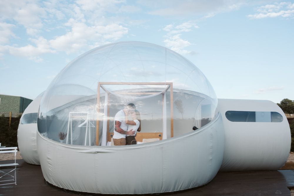 Affectionate couple looking at each other and kissing near bubble hotel