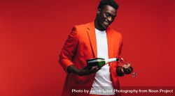 Handsome young Black man pouring champagne in the glass 4OMVZ0