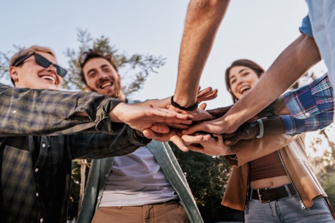 Low angle view of diverse friends with hands together in a huddle.