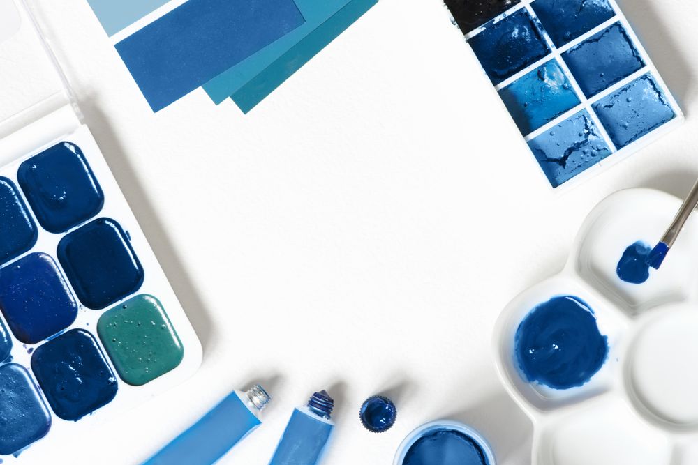 Blue paint palette and tubes on bright background with copy space