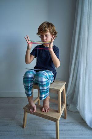 Boy playing with colorful strings at home