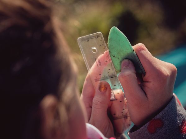 Crop preteen girl measuring piece on plastic with ruler