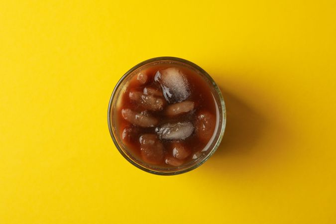 Glass of ice coffee on yellow background. Fresh drink