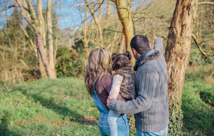 Back of parents with small daughter looking out to forest