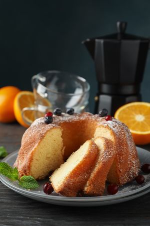 Cake with powdered sugar, berries and mint on wooden background, copy space