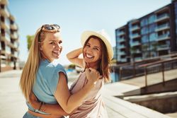 Two female friends looking back and smiling along the river on a sunny day, copy space