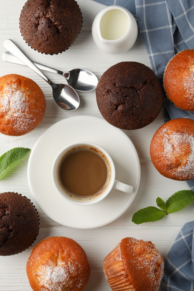 Composition with muffins and cocoa drink on light wooden background