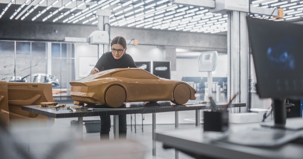 Car Modeler Enjoying Creative Work Process on a Concept Car Made Out of Plasticine Modeling Clay.