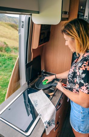 Female cleaning up pan in small motorhome kitchen
