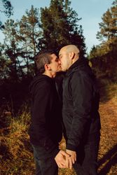 Men holding hands and kissing in park