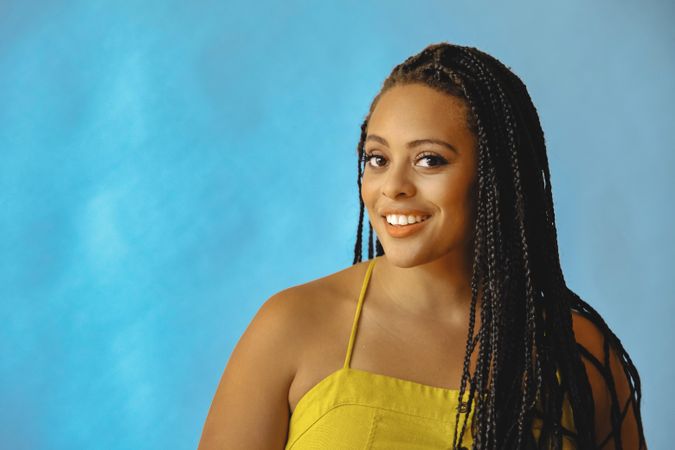 Portrait of expectant female with long braided hair in yellow shirt, copy space