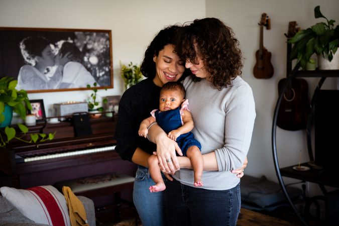 Two women with their curious baby girl at home